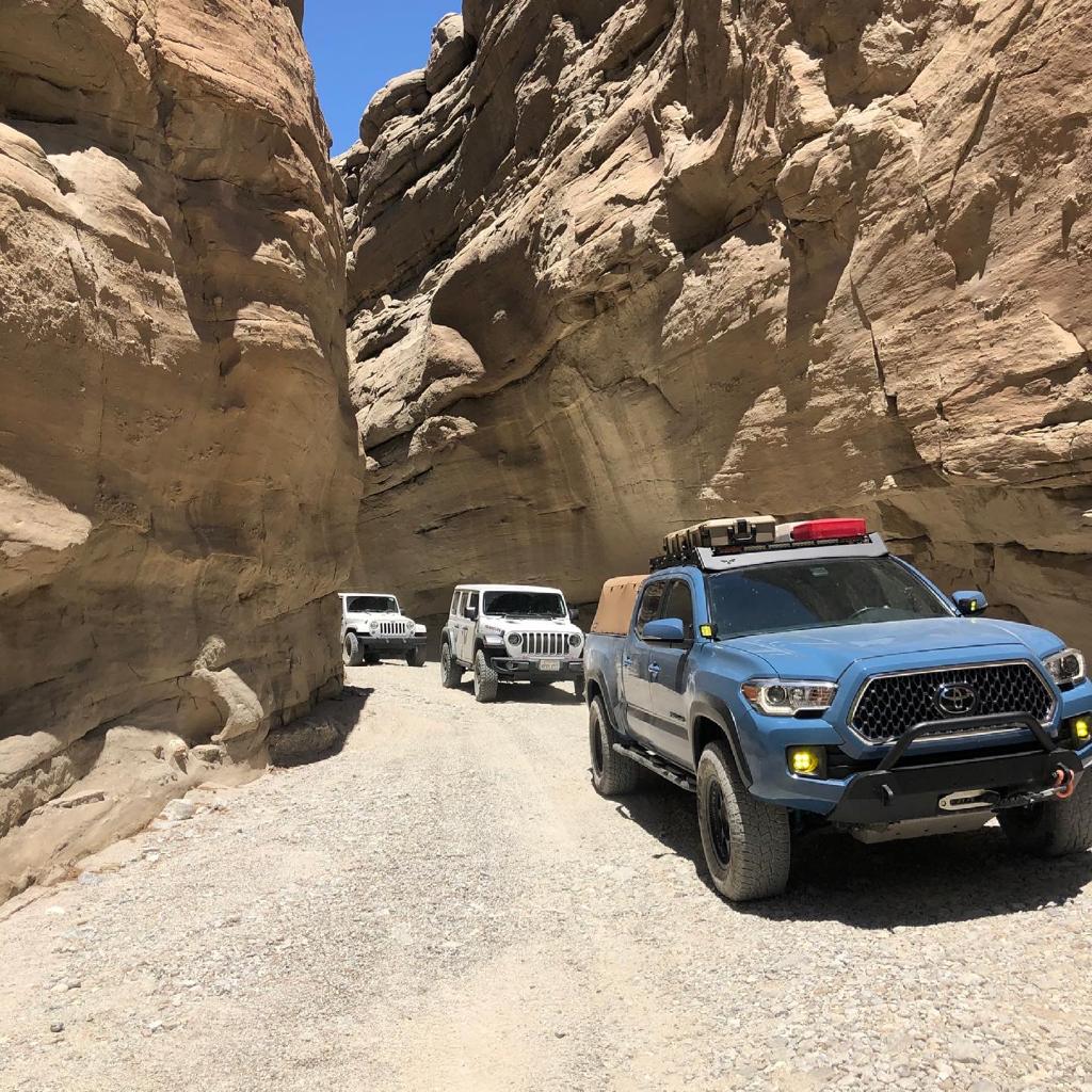 Blue Toyota Tacoma and white Jeeps offroad in a desert canyon in Anza Borrego Desert State Park, California