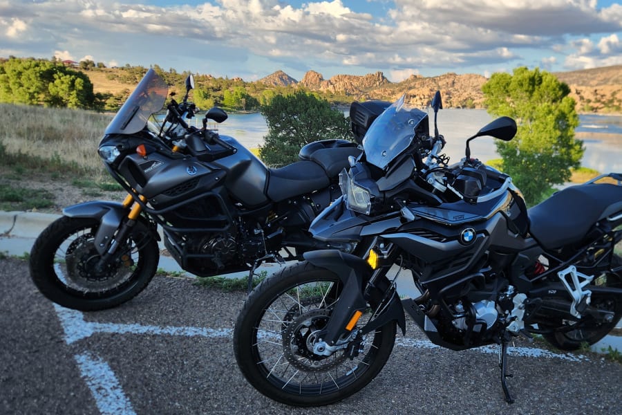Two adventure motorcycles are shown with Lake Watson in Prescott, AZ, in the background