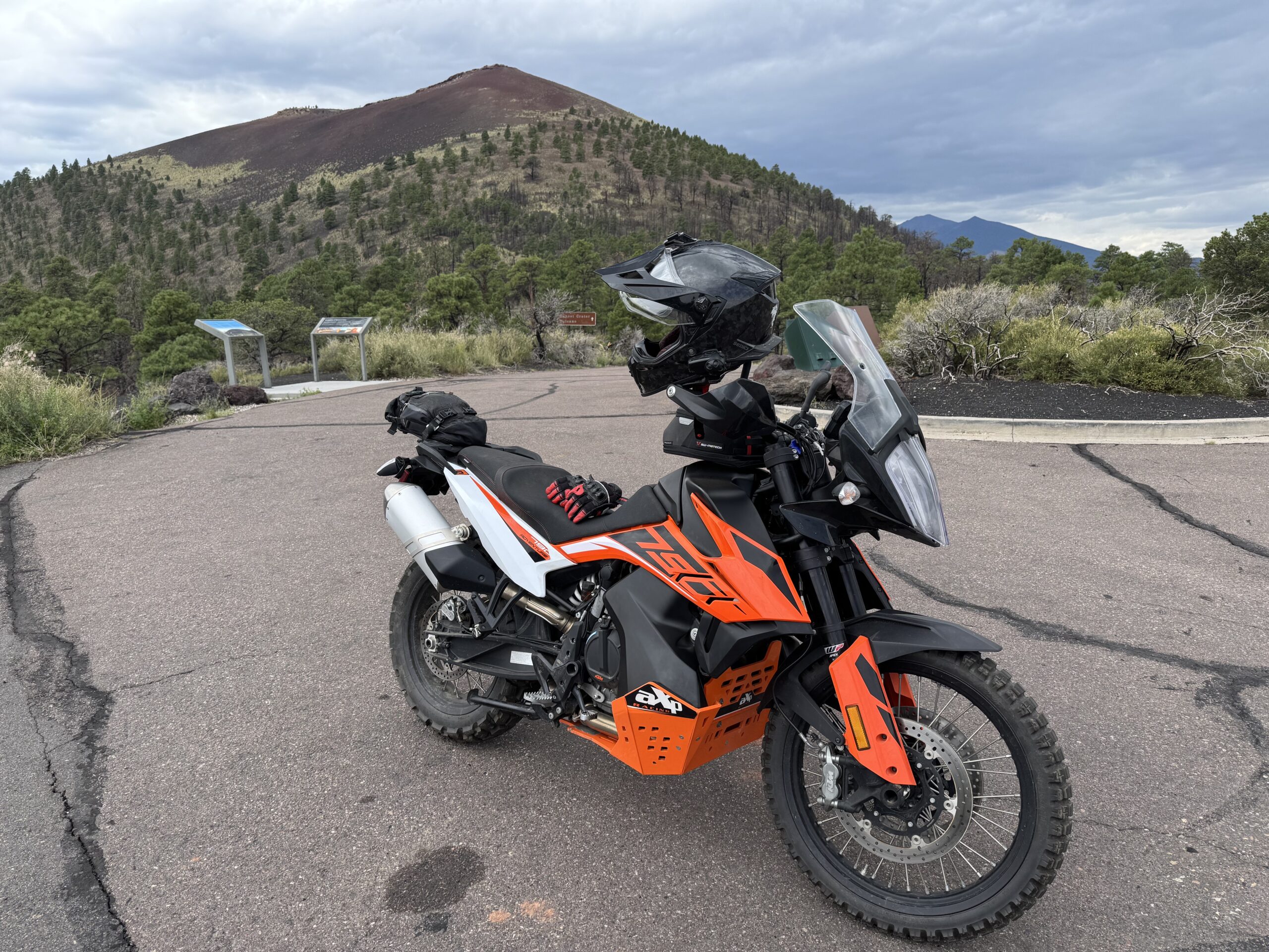 A 2020 KTM 790 Adventure S adventure motorcycle is parked in front of Sunset Crater, a prominent volcanic summit near Flagstaff, AZ.