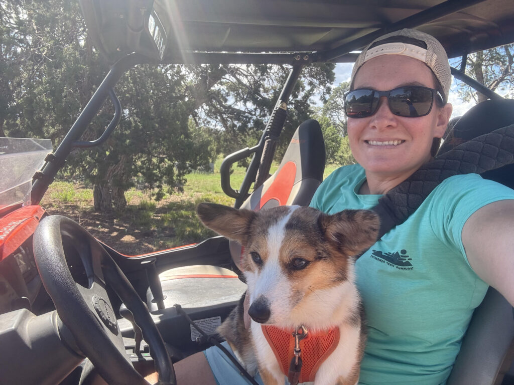 A girl takes a selfie with a dog on her lap in an orange UTV