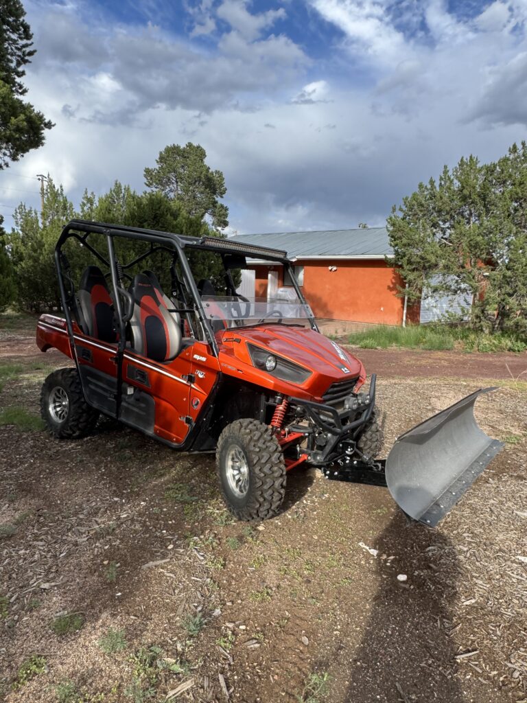 An orange UTV with a snowplow mounted to the front.